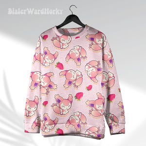 May include: Pink sweatshirt with a repeating pattern of cartoon characters and strawberries. The characters are pink and white with purple accents. The strawberries are red. The sweatshirt is hanging on a black hanger.