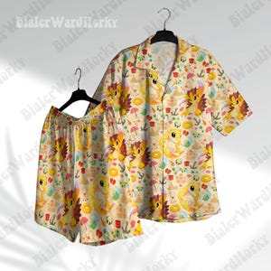 May include: A matching set of beige Hawaiian shirt and shorts. The shirt has short sleeves and a button-down front. Both pieces feature a repeating pattern of cartoon characters, beach elements, and anchors. The color palette includes yellow, orange, and brown.