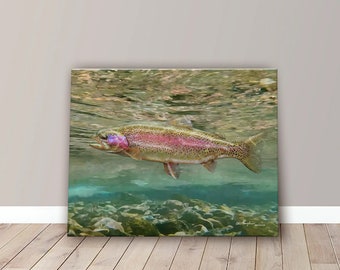 May include: A canvas print of a rainbow trout swimming underwater. The fish has a pink stripe along its side and is surrounded by clear water and rocks. The artwork is displayed on a wall with a wooden floor.