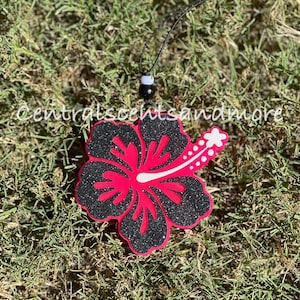 May include: A black and pink glitter hibiscus flower car air freshener with a black string.