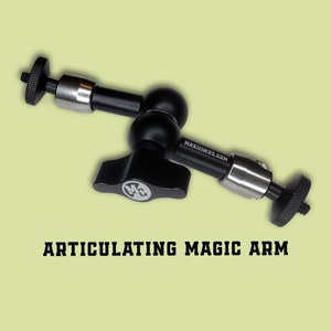May include: Black articulated magic arm with two ball joints and a silver knob. The arm is labelled "MAXIIMUS.COM".