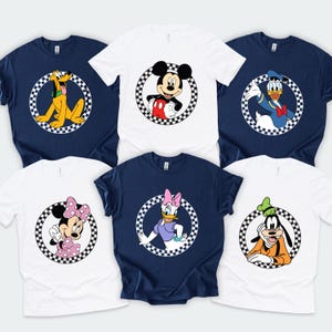 Pu&ograve; includere: Una collezione di sei magliette a maniche corte bianche e blu navy, ognuna con una grafica circolare di un classico personaggio dei cartoni animati incorniciato da un bordo a scacchi bianco e nero. I personaggi includono Topolino, Minnie, Paperino, Paperina, Pippo e Pluto.