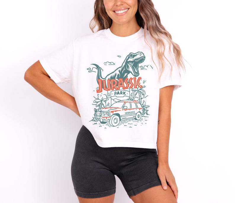 Pu&ograve; includere: Una t-shirt bianca a maniche corte con una stampa grafica di un dinosauro T-Rex, una scena nella giungla e un veicolo con la scritta Jurassic Park in inchiostro rosso e verde. La maglietta &egrave; abbinata a pantaloncini neri a coste testurizzati.