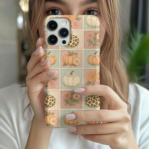 May include: A smartphone case featuring a grid pattern of alternating squares in soft pink, sage green, and cream. The design includes illustrations of pumpkins, orange and pink chrysanthemums, and pumpkins with a brown and black leopard print pattern.