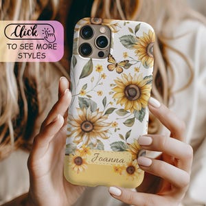 May include: A white smartphone case featuring a pattern of yellow sunflowers, green leaves, and a small butterfly. The case includes a rectangular yellow label at the bottom with the name Joanna printed in a cursive black font on the surface.