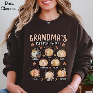 May include: A dark chocolate brown crewneck sweatshirt featuring the text "GRANDMA'S PUMPKIN PATCH" in a light peach font. Below the text are eight illustrated pumpkins with various patterns and colors, each labeled with a name: Sophia, Teo, Alex, Charlotte, Dylan, Felix, Eliza, and Jaxson.