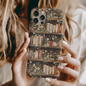 May include: A phone case with a floral design and a bookshelf with books. The case is brown and has a floral pattern with a bookshelf with books. The phone case is for an iPhone 13 Pro Max.