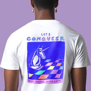 Könnte beinhalten: Weißes T-Shirt mit einem farbenfrohen Aufdruck auf dem Rücken. Das Design zeigt eine Einhorn-Schachfigur auf einem Schachbrett mit den Worten "Let's Conqveer the World with Love."