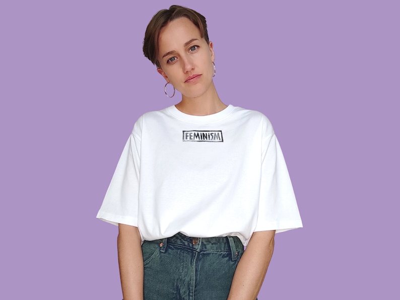 May include: A white t-shirt with the word "FEMINISM" printed in black on the front.