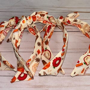 May include: Three fabric headbands with a fall-themed print featuring donuts, coffee cups, and apples on a cream background.