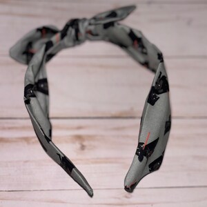 May include: A gray headband with a black and white print of a Star Wars character. The headband is tied in a knot at the top.