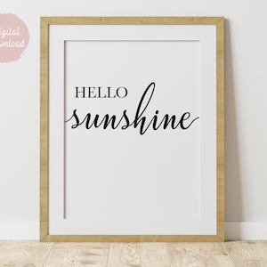 Puede incluir: Una impresión enmarcada con fondo blanco y texto negro que dice "HELLO sunshine" en una fuente cursiva.