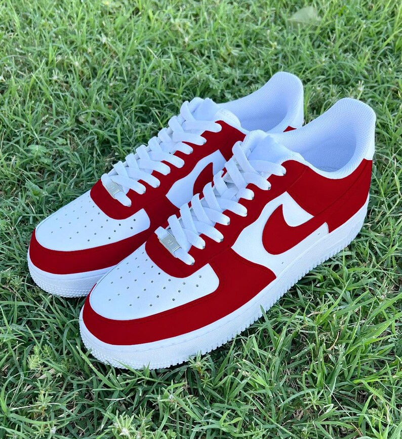 Pu&ograve; includere: Un paio di scarpe da ginnastica bianche e rosse con un logo Swoosh rosso. Le scarpe hanno una suola bianca e una tomaia rossa.