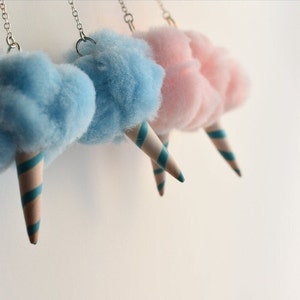 May include: Three cotton candy earrings, two blue and one pink, hanging from silver chains. Each cotton candy is attached to a striped paper cone.