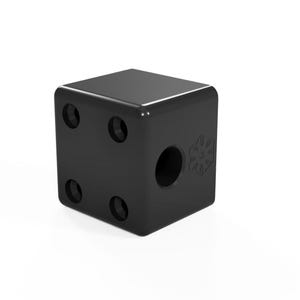 Puede incluir: Objeto negro en forma de cubo con cuatro agujeros y un recorte circular en un lado.