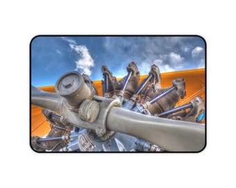 May include: Close-up of a vintage aircraft engine with a propeller. The engine is made of metal and has a radial design. The propeller is made of wood and has a yellow and orange paint scheme.