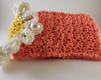 May include: A crocheted peach-colored pouch with a white crocheted flower and a pearl embellishment.
