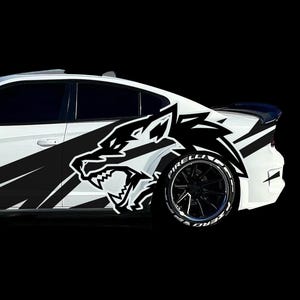 May include: White car with black wolf head graphic on the side. The car has black wheels with white lettering on the tires. The design includes black angled stripes. The background is black.