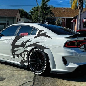 May include: A white Dodge Charger with black and white graphic decals on the side and rear. The car has black wheels and a black spoiler.