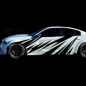 May include: White car with black accents and black wheels. The car has a sleek design with black graphic patterns along the side. The tires have white lettering. The car is set against a black background.