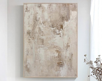Op de afbeelding: Abstract schilderij in beige en bruine tinten. Het schilderij is ingelijst in een dun, gouden lijst en hangt aan een witte muur.