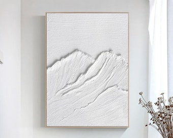 Puede incluir: Pintura abstracta blanca con un diseño texturizado y en relieve de montañas. La pintura está enmarcada en un marco fino y dorado.
