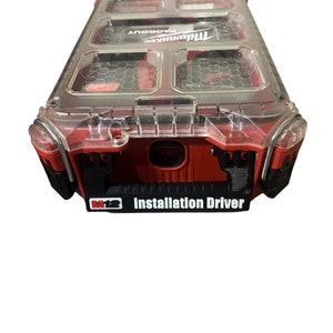 May include: Red and black Milwaukee Packout tool box with a clear lid. The box has a label that says "M12 Installation Driver".