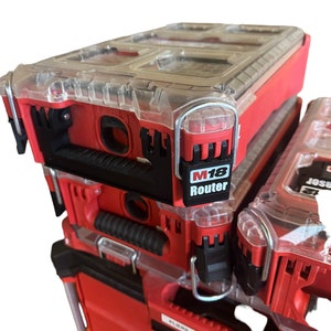 May include: A stack of three red and black toolboxes with clear plastic lids. The top toolbox has a label that says "M18 Router".