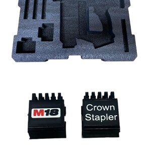 Puede incluir: Dos cajas de herramientas negras con un inserto de espuma. Una caja tiene el texto "M18" en letras rojas y blancas. La otra caja tiene el texto "Crown Stapler" en letras blancas.
