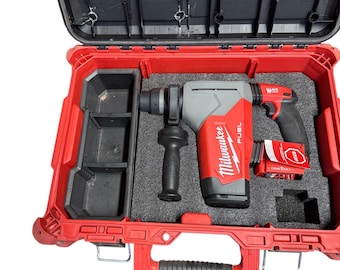 May include: A red and black hard case containing a grey and red power tool. The tool features a black handle and a battery pack. The case is open, showing a black interior with compartments for the tool and accessories.