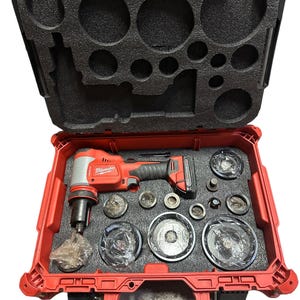 May include: A red Milwaukee tool case with a black foam interior. The case contains a cordless hole cutter and various sized hole saw blades.
