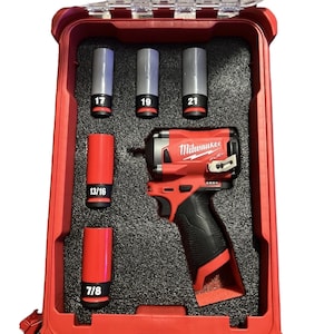 Peut inclure: Un tournevis à percussion Milwaukee Fuel rouge avec une poignée noire et un étui en plastique transparent. L'étui contient une variété de douilles à percussion, notamment 7/8, 13/16, 17, 19 et 21 mm.