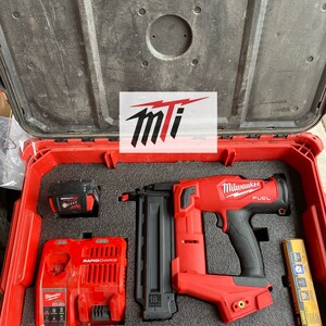 Puede incluir: Una clavadora de brad de calibre 18 Milwaukee FUEL roja con mango negro y un cargador de bater&iacute;a rojo y negro en una caja de herramientas roja. La clavadora tiene un cargador negro y un gatillo negro. El cargador de bater&iacute;a tiene el texto "RAPIDCHARGE" en &eacute;l. La caja de herramientas tiene el texto "Milwaukee" en ella.