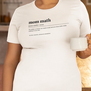 Puede incluir: Camiseta blanca con el texto "mom math" definido como "la capacidad de dividir un refrigerio de manera uniforme entre tres niños mientras se hace parecer justo."
