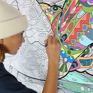 May include: A person coloring a large, detailed, black and white drawing of a bird with a blue marker. The bird is surrounded by waves and fish. The drawing is on a white background.