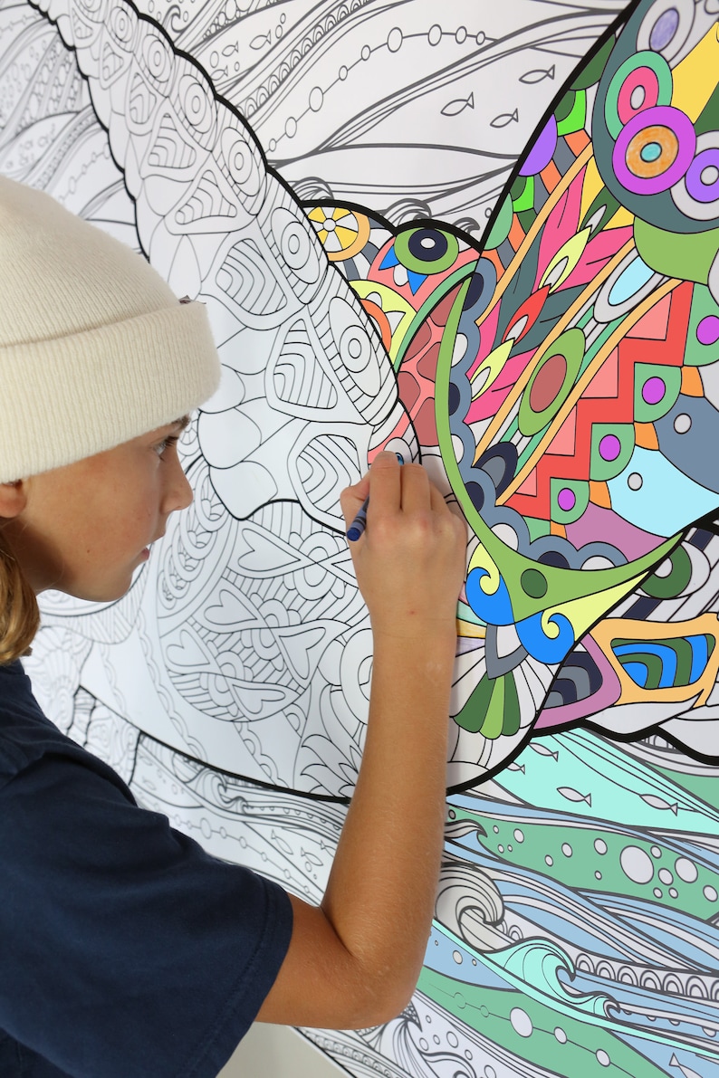 May include: A person coloring a large, detailed, black and white drawing of a bird with a blue marker. The bird is surrounded by waves and fish. The drawing is on a white background.