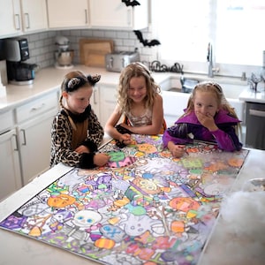 May include: A large rectangular Halloween-themed coloring poster featuring intricate illustrations of pumpkins, ghosts, skeletons, spider webs, and candy corn, partially colored with markers by three children sitting at a kitchen counter.