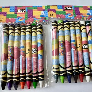 May include: Two packages of colorful crayons with LEGO branding. Each package contains eight crayons with a LEGO brick pattern.