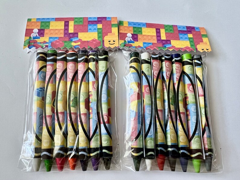 May include: Two packages of colorful crayons with a Lego-themed design. Each package contains 8 crayons with a variety of colors.