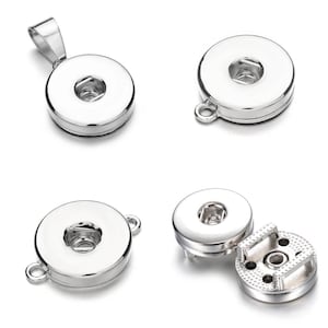Könnte beinhalten: Vier silberfarbene Magnet-Druckknöpfe. Zwei davon sind mit einer Schlaufe zum Anbringen an einer Halskette oder einem Armband gezeigt. Einer ist mit zwei Schlaufen zum Anbringen an Stoff gezeigt. Der letzte ist mit einem Rückenteil zum Anbringen an Stoff gezeigt.