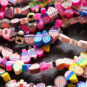Könnte beinhalten: Eine Sammlung bunter Polymer Clay Charms in Form verschiedener Desserts, darunter Cupcakes, Eiswaffeln und Spiralen. Die Charms sind perfekt für die Schmuckherstellung, das Scrapbooking und andere Bastelprojekte.