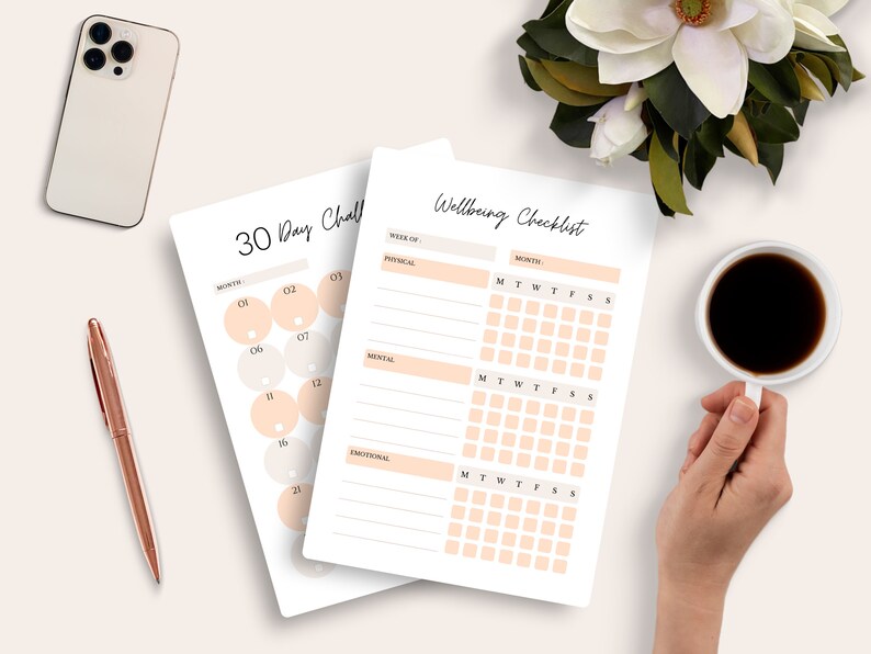 May include: Two white paper checklists, one labeled "30 Day Challenge" and the other "Wellbeing Checklist", are displayed on a light surface. The "30 Day Challenge" checklist has numbered circles. The "Wellbeing Checklist" has sections for physical, mental, and emotional well-being.