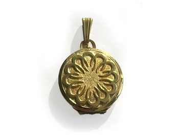May include: A gold-toned locket pendant with a detailed floral design. The locket is round and has a hinged opening.