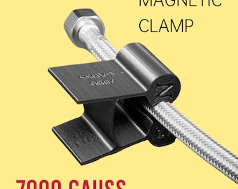 Può includere: Un morsetto magnetico nero con una potenza di 7000 Gauss, progettato per tenere in posizione un tubo o un cavo. Il morsetto è realizzato in plastica resistente e presenta una forte forza magnetica.