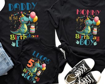 May include: Black t-shirts with birthday graphics. One reads "DADDY of the Birthday Boy", another "MOMMY of the Birthday Boy", and a third "LUCAS 5 Birthday Boy". Each shirt features a cartoon dinosaur, balloons, and a cake, perfect for a family.