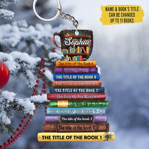 May include: A colorful book stack keychain with a coffee mug charm. The mug has the name "Sophia" on it. The books have titles like "The Title of the Book 1" and "The Title of the Book 2". The keychain is a fun and unique gift for book lovers.