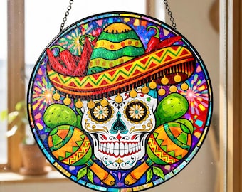 May include: A round, stained-glass window decoration featuring a colorful Day of the Dead sugar skull design. The skull has floral accents, a sombrero, maracas, and cactus. The artwork is framed in black and hangs from a chain.