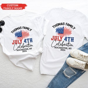 K&ouml;nnte beinhalten: Zwei wei&szlig;e T-Shirts mit einem verwitterten amerikanischen Flaggen-Design und dem Text "Thomas Family July 4th Celebration Rochester, NY 2024".