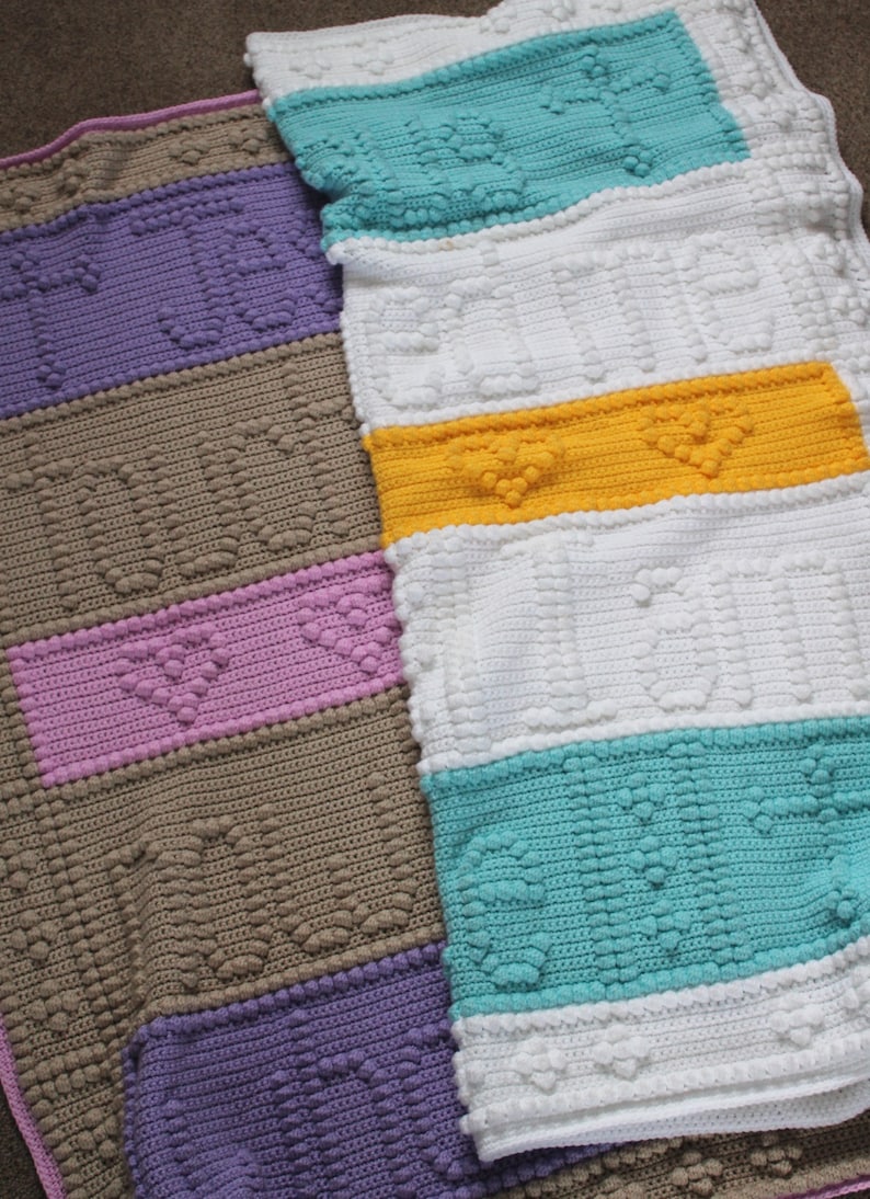 May include: A multi-coloured crocheted blanket with a textured heart pattern. The blanket is made up of stripes of purple, brown, pink, white, yellow, and turquoise.