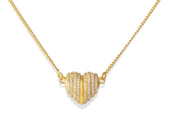 May include: A gold-colored necklace featuring a heart-shaped pendant. The pendant is split in the middle and encrusted with small, clear gemstones. The necklace chain is a delicate curb link style.
